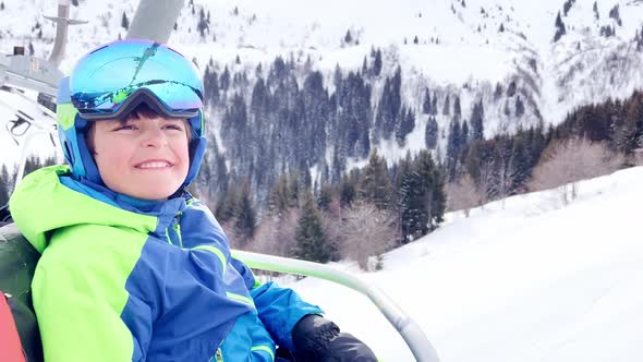 Close Portrait of a Boy with Ski Going Up on Chairlift