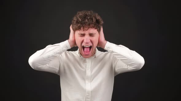 Young Stressed Man Covering Ears with Hands Screaming Shouting