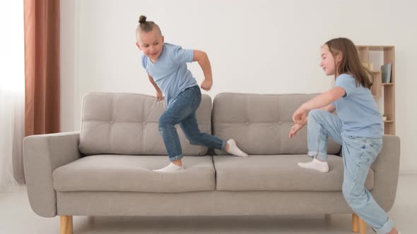 Two Children are Playing on the Couch They are Having Fun Jumping in the Living Room