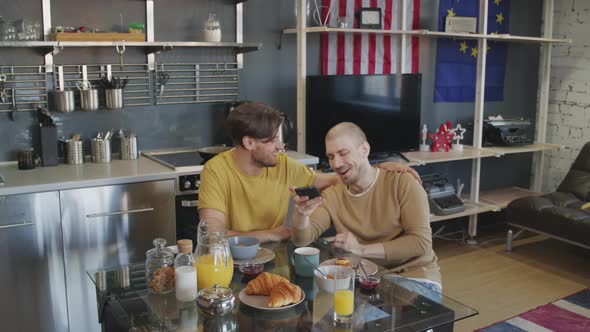 Same-Sex Couple Laughing while Using Mobile Phone