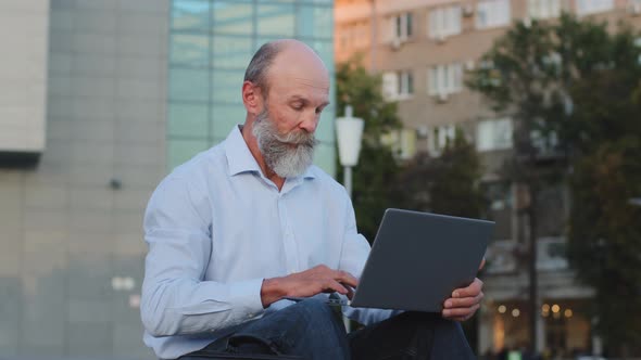 Elderly Active Pensioner Sitting Outdoors Using Laptop Works Remotely Online