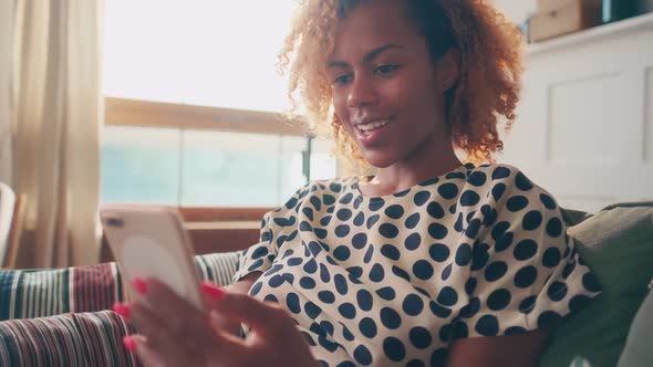 Young African American Woman Making Video Call on Phone Sits in Living Room