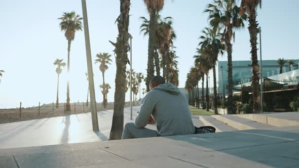 Bald sportsman texting by phone while sitting outdoors