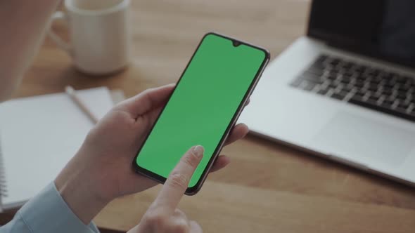 Woman Holding a Smartphone in the Hands of a Green Screen Chroma Key Flips a Finger on the Screen