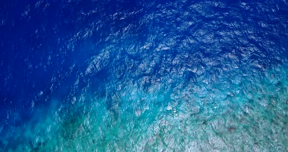 Wide angle flying tourism shot of a white paradise beach and blue sea background in hi res