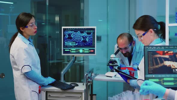 Nurse Holding Tablet Computer and Chemist Using Microscope