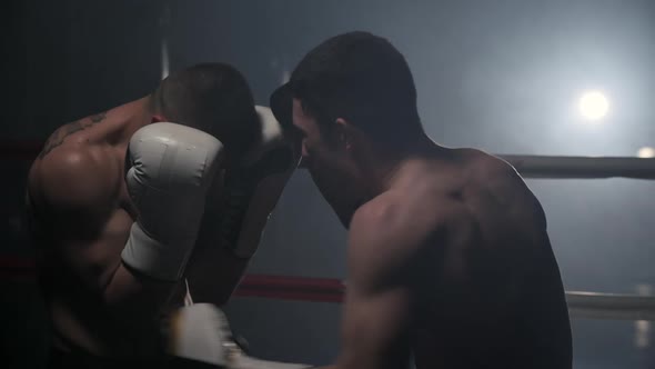 Cinematic Slow Motion Shot of Two Professional Young Muscular Shirtless Male Boxers Fighting in a