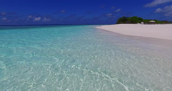 Wide fly over clean view of a white paradise beach and aqua turquoise water background in 4K