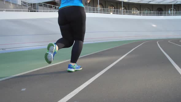 Legs of Overweight Woman Jogger on Stadium Track