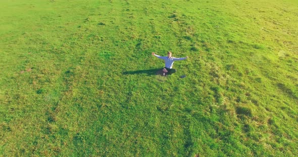 Low Orbital Flight Around Man on Green Grass with Notebook Pad at Yellow Rural Field.