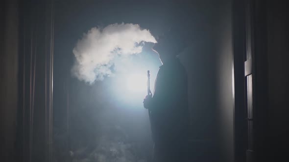 a Man in a Hookah Exhales Smoke