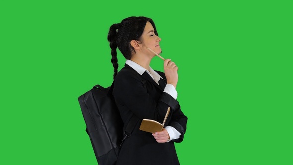 Pretty student with backpack writing notes on a Green Screen