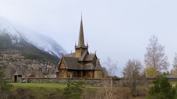 Traditional Wooden Church At Lom Stavkyrkje With Stoned Wall Fence In Norway. Aerial Ascending