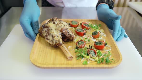 Chef Demonstrates a Lamb Dish Along with Vegetables Tomatoes and Greens