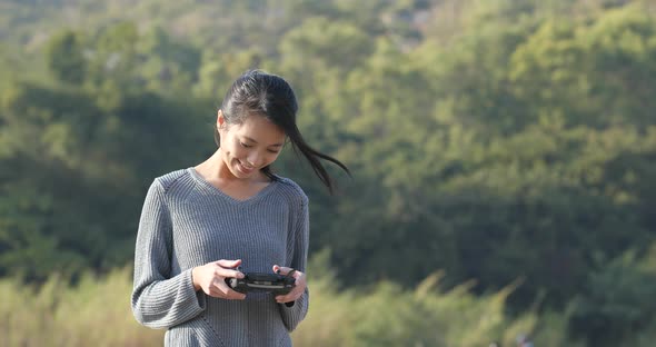 Woman controling flying drone in the park