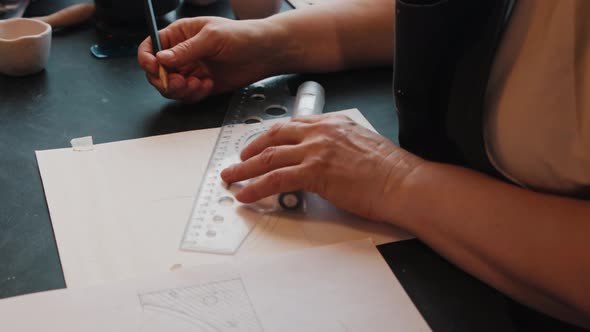 An Elderly Woman Designer Sketching on the Paper Using Pencil and Ruler
