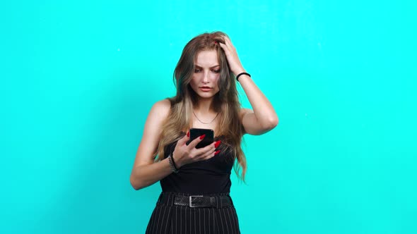 The Puzzled Young Woman Receives a Message on the Phone and Is Saddened.