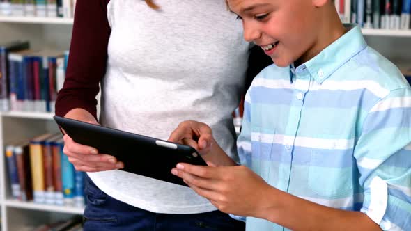 Happy students using digital tablet in library