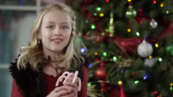 Young girl turns and smiles while holding candy canes