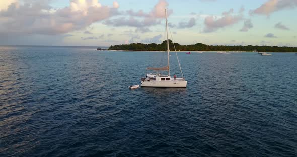 Tropical aerial tourism shot of a summer white paradise sand beach and blue water background in 4K