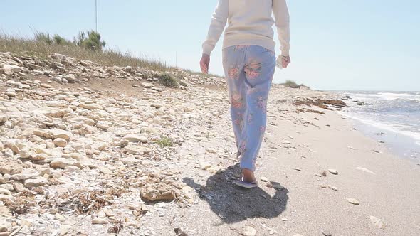 Slow Motion Steadicam Footage of a Girl Walking Along the Shoreline of the Sea in Windy Weather