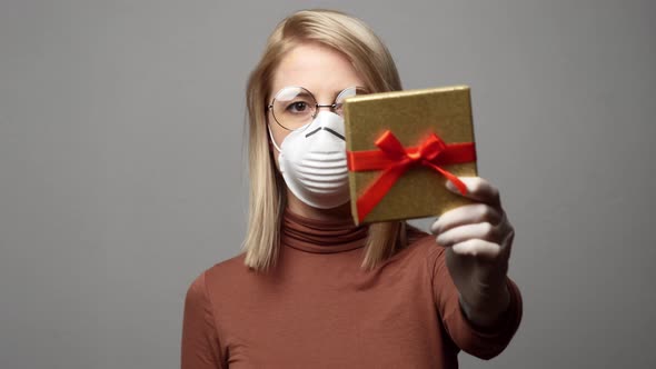 Style blonde woman in face mask with gift box on white background