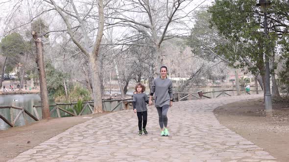 Smiling sportswoman with son walking on footpath in park