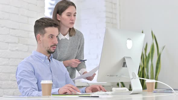 Focused Creative Team Reading Documents and Working on Desktop