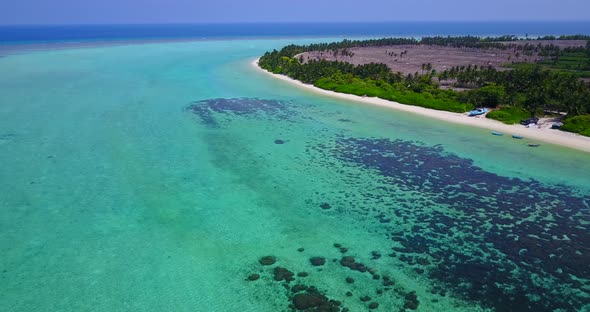 Daytime fly over tourism shot of a white sandy paradise beach and aqua blue water background in colo