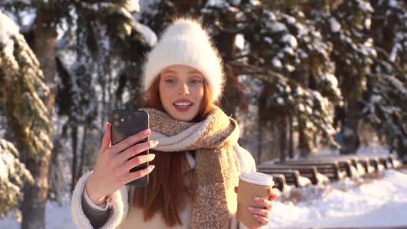 Portrait of Happy Young Woman Talking on Video Call Via Mobile Phone and Holding Cup with Hot Coffee