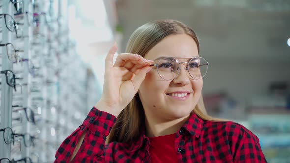 Woman choosing new glasses. Happy young woman choosing glasses in optics store