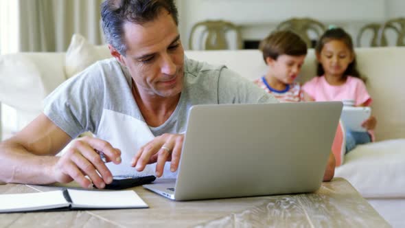 Tense man using calculator in living room