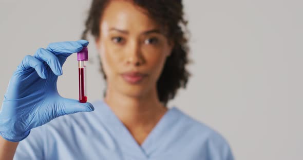 Video of biracial female doctor holding test tube on blue background