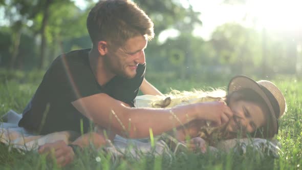 Joyful Man Laughing Tickling Girl Lying in Sunbeam on Spring Summer Lawn in Park