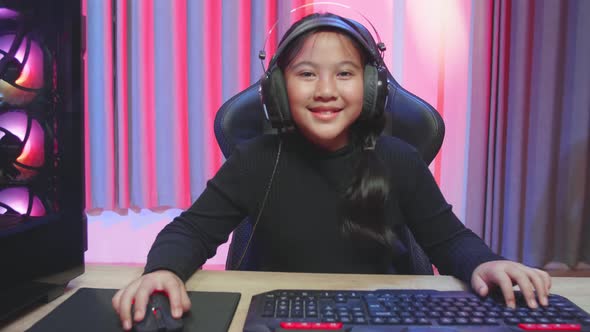 Young Gamer Girl With Headphones Plays Video Game On A Computer Feeling Relax And Looking At Screen