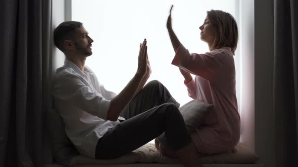 Cute Couple Sitting Together on the Windowsill Playing Pat-a-cake. Husband and Wife Resting at Home