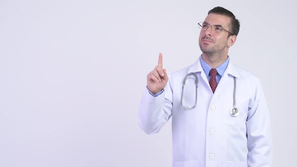 Young Happy Hispanic Man Doctor Thinking While Pointing Up