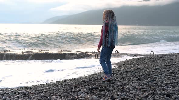 Little Girl Watching Stormy Waves on the Beach