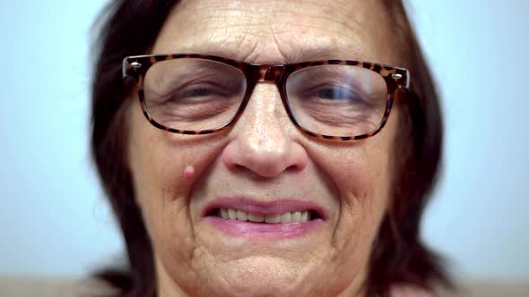 Mature Woman In Glasses Portrait Close Up. Mature Cheerful Aged Retired Grandmother Sitting On Sofa.