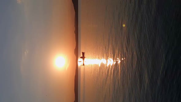 Dinghy slowly motors through waters of calm harbor at sunset. Vertical video