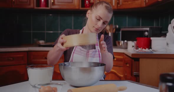 Woman Sifts Flour Through Sieve in the Kitchen While Baking Croissants