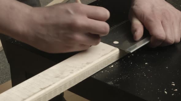 Small pine lumber board is marked square with edge of box hand saw