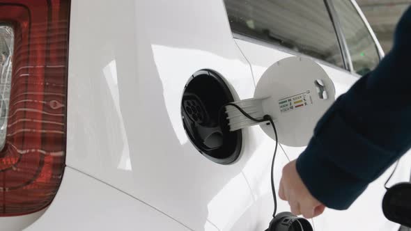 Close Up Woman Hand Unplugging the Cable of Electric Vehicle