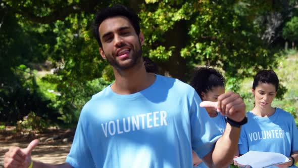 Smiling volunteer pointing at his t-shirt 4k