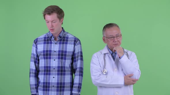 Stressed Mature Japanese Man Doctor with Young Man Thinking Together