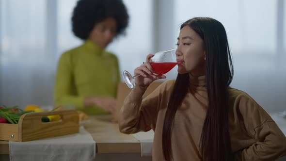 Young Attractive Asian Woman Drinking Red Wine in Slow Motion and Smiling Looking at Camera with