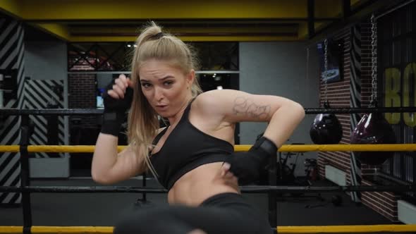 Athletic Female Kickboxer Practices Kicking in the Boxing Ring in the Gym