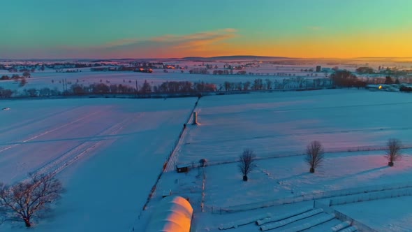 Aerial View Across Countryside Farmlands After a Early Morning Snow Fall During the Golden Hour