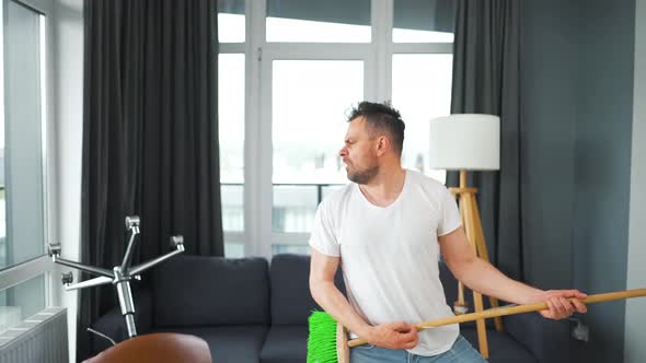 Man Does the Cleaning and Imagines Himself a Rock Star Plays the Broom Like a Guitar