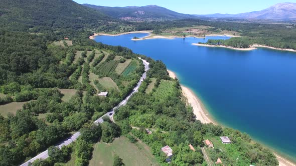 Aerial view of red van driving on dalmatian highway by artificial lake Peruca